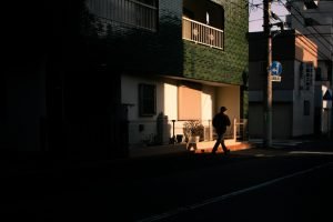 A person walks on a street in sunlight.